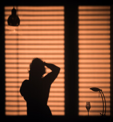 silhouette of a person at the window blinds