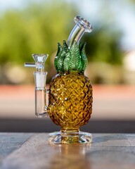 Closeup shot of a glass pineapple bong set on a table outoors