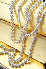 Close-up of a pearl necklace over gold bars