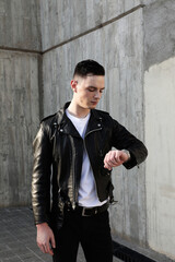 Young stylish man wearing leather jacket posing in the street. Vertical.