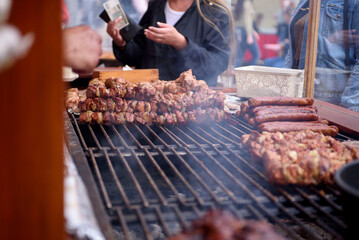 Cooking meat dishes in a summer restaurant on the street. Assorted delicious grilled meat with vegetables over charcoal barbecue.