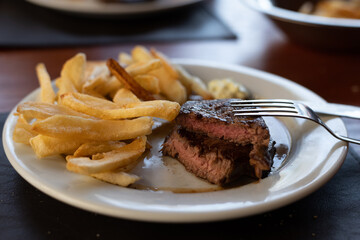 plate of beef tenderloin with french fries in restaurant