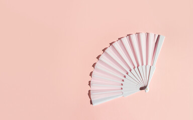 White fan on a pastel background. Minimal creative concept of menopause and female hot flashes. Copy space, flat lay