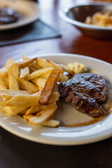 plate of beef tenderloin with french fries in restaurant