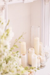 Classic fireplace in wedding decor. Candles in glass vases surrounded by white flowers. Selective focus.