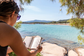 Teen girl reading a book and relaxing on a sunbed at the beach