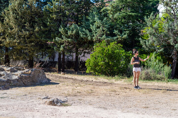 Pretty young hipster woman with sunglasses, holding smartphone in hands and making a video call standing outdoors.