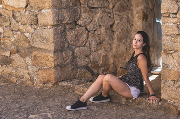 Portrait young attractive woman look at camera serious sitting over isolated stone wall background