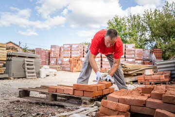 man construction industry or warehouse worker stacking clay brick