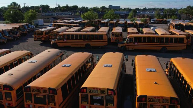 The parking full of school buses waiting for educational season. Row filled with many school bus ready to pick up students to school. Aerial view.