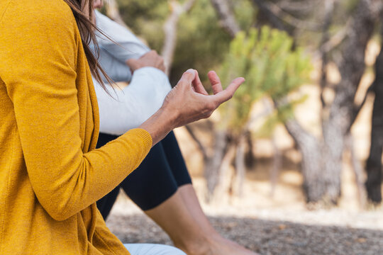 woman practising prithvi mudra yoga posistion with her fingers on a mindfulness group therapy