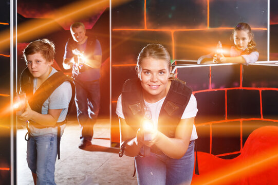 Glad Teen Boy With Laser Gun Having Fun On Laser Tag Arena With His Older Sister