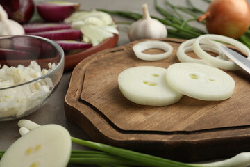Fototapeta na wymiar Fresh onion and wooden board on grey table, closeup