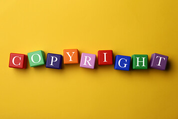 Plagiarism concept. Word Copyright made of color cubes on yellow background, top view