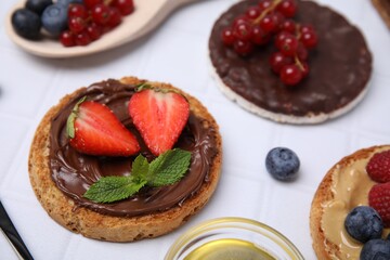 Fresh rice cake and rusks with different toppings on white table, closeup