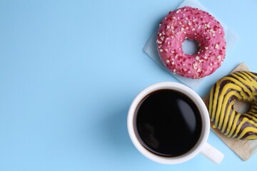 Tasty frosted donuts and cup of coffee on light blue background, flat lay. Space for text