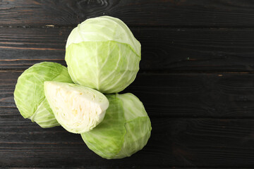 Ripe white cabbage on black wooden table, flat lay. Space for text