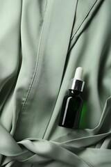 Bottle of hydrophilic oil on green fabric, top view