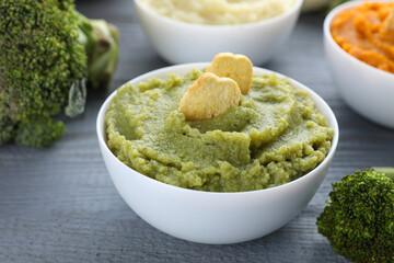 Bowl with tasty green puree and ingredients on light blue wooden table, closeup