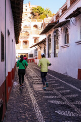 Two people running in a street of a magical town in Taxco Mexico