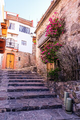 Colonial, cobbled street adorned with red flowers in Taxco, Mexico.