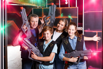 Nice teens and theirs parents with laser guns during laser tag game indoors