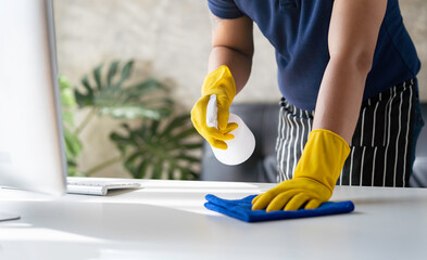 Close-up, restaurant staff's hands are cleaning table surfaces and spraying disinfectant during the...