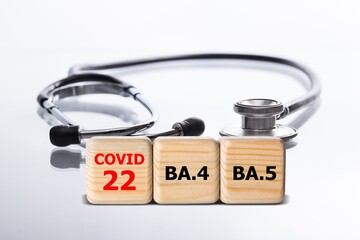Wooden blocks on the desk. Scientific symbols of the coronavirus evolved from the omicron. The...