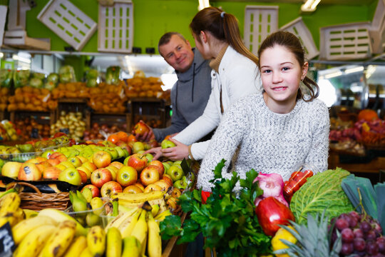 Portrait of satisfied tweenage girl during family shopping in fruit store
