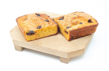 piece of craft cornbread home made Johnny bread made of corn flour and fig pieces on a wooden cutting board isolated on a white background