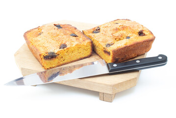 piece of craft cornbread home made Johnny bread made of corn flour and fig pieces on a wooden cutting board with a knife at the side as adornment isolated on a white background