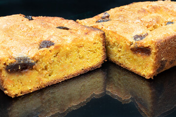 piece of craft cornbread home made Johnny bread made of corn flour and fig pieces on an elegant black background with reflection
