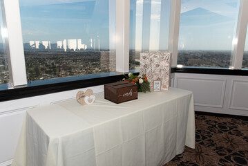 Reception venue has table set up for guests to fill out well wishes cards along with a beautiful window view of the city