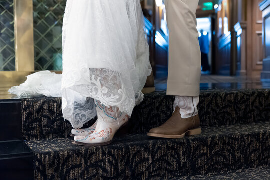 Bride and groom showing off their cowboy and cowgirl boots during the wedding ceremony