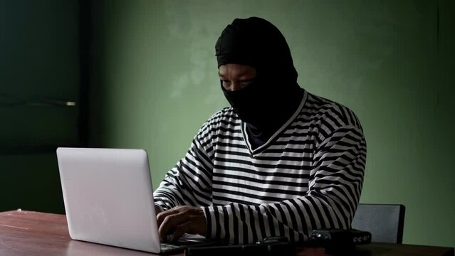 Thief use computer for theft. Hacker stealing data from a laptop concept for network security and computer crime.