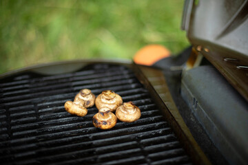 Mushrooms are grilled. Picnic details. Food on steel grate.