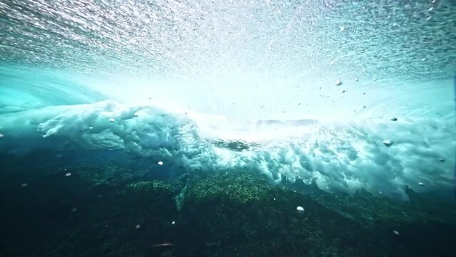 Underwater shot of blue wave barrel forming and breaking. Teahupoo famous surfing action sports destination in Tahiti. surf destination travel in French Polynesia. slow motion. 