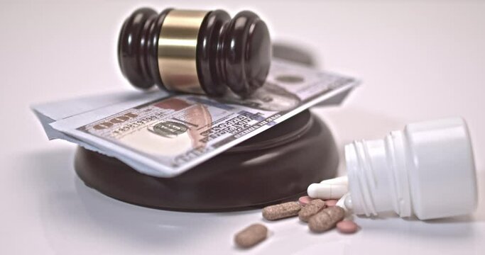 Pills and can of pills falling on a judge's gavel on a white background. Concept For Medical Negligence, Bail, Monetary Compensation, Drugs Falsification.