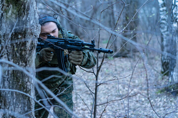soldier in the forest. a man in military uniform in the branches of trees, in an ambush with a...