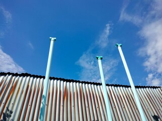 Plastic ventilation pipe and metal roof. Three blue PVC pipes beside galvanized roof for...