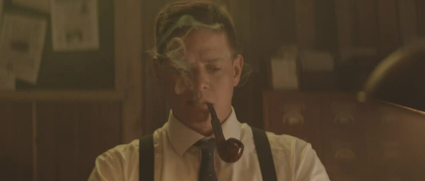 Mid adult Caucasian officer smoking pipe. Retro style detective using deduction for solving challenging cases.