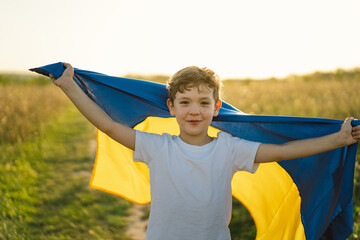 Ukraine's Independence Day. Ukrainian child boy in white t shirt with yellow and blue flag of Ukraine in field. Flag of Ukraine. Constitution day. Stand with Ukraine and Save