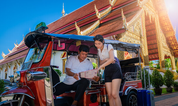 Young and beautiful tourist gets information and discusses the price with a tuk tuk driver in Chiang Mai. Tuk tuk is a quick, typical and practical way of commuting in town.