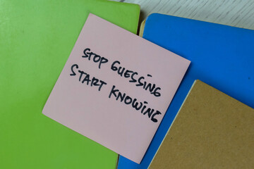 Concept of Stop Guessing, Start Knowing write on a book isolated on Wooden Table.