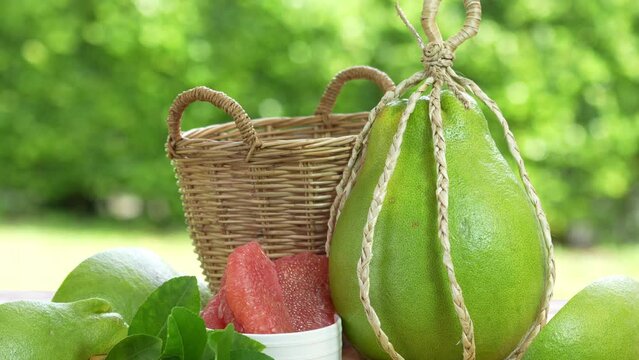Pomelo fruit in wooden basket on blur garden background, Red Pomelo fruit with slice in wooden basket.