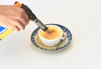 the process of lighting brown sugar on the Creme brulee on white background