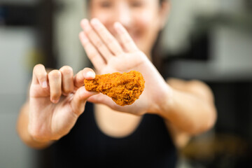 Beautiful female in sportswear fried chicken junk food high calorie food and health risks. Hungry young woman eating Fried Chicken