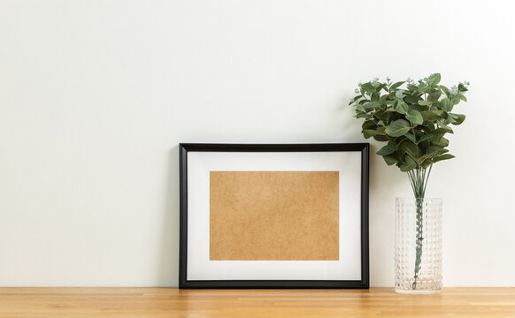 Style picture frame still life put on the wooden table. Blank space empty picture frame with mockup. Shot in studio with natural light. Template background interior design and decoration.
