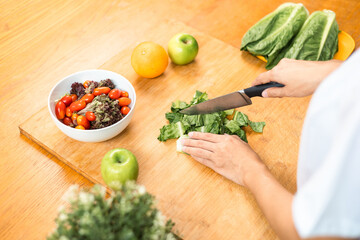 Female slicing and cooking green apple on cutting board for vegetable salad in weight loss diet. Beautiful woman happily cooks a healthy breakfast in kitchen in the morning. Diet food concept.