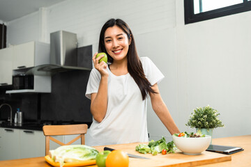 Young female eating organic greens vegetable salad in weight loss diet and wellness on table. Beautiful woman happily eat a healthy salad breakfast in kitchen in the morning. Diet food concept.